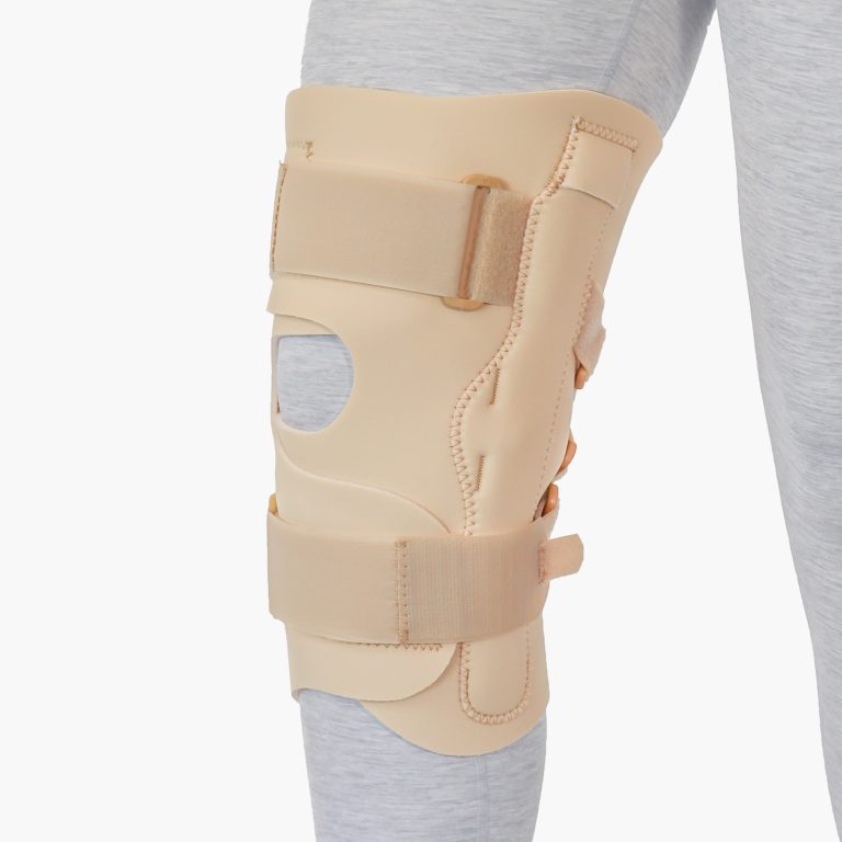 Studio shot of the beige TheraCore HyperEx knee brace featuring rigid hinges and tension straps for advanced hyperextension control.